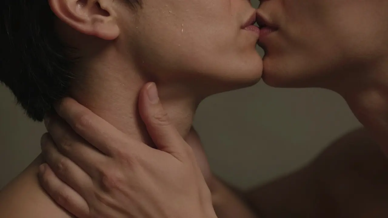 Close-up of a partner giving a shoulder massage and a gentle kiss on the neck.